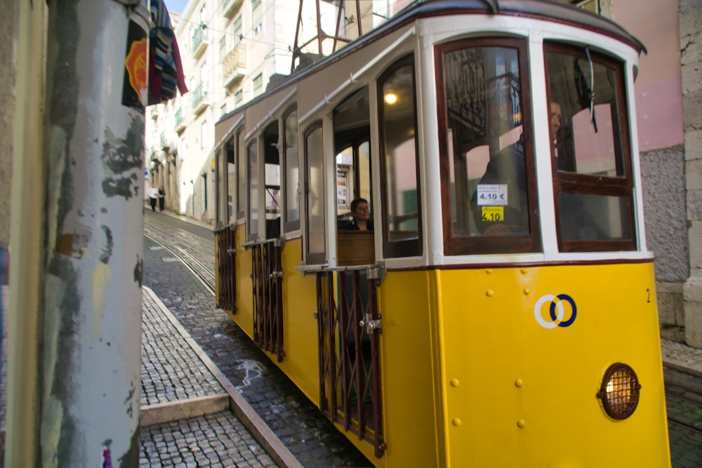 a yellow trolley car on a cobblestone street