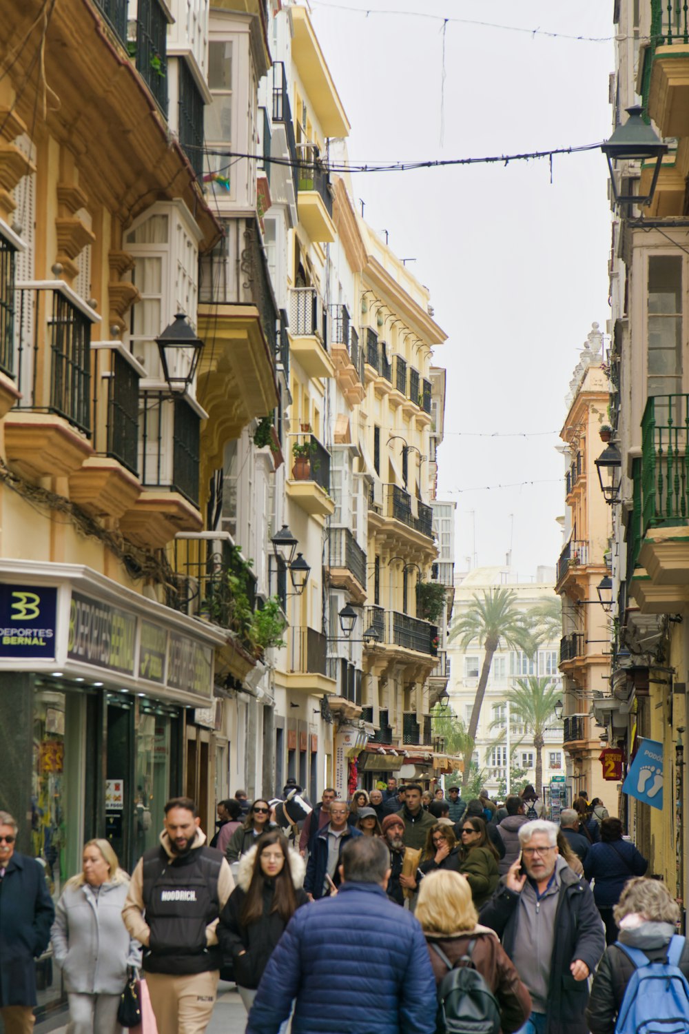 a crowd of people walking down a street next to tall buildings