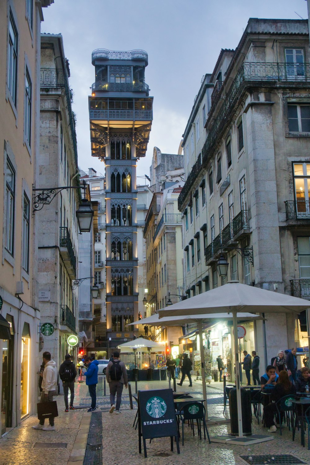 a group of people walking down a street next to tall buildings