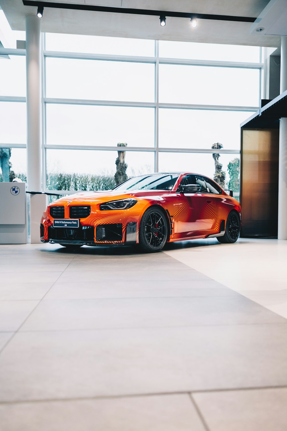 an orange sports car parked in front of a large window