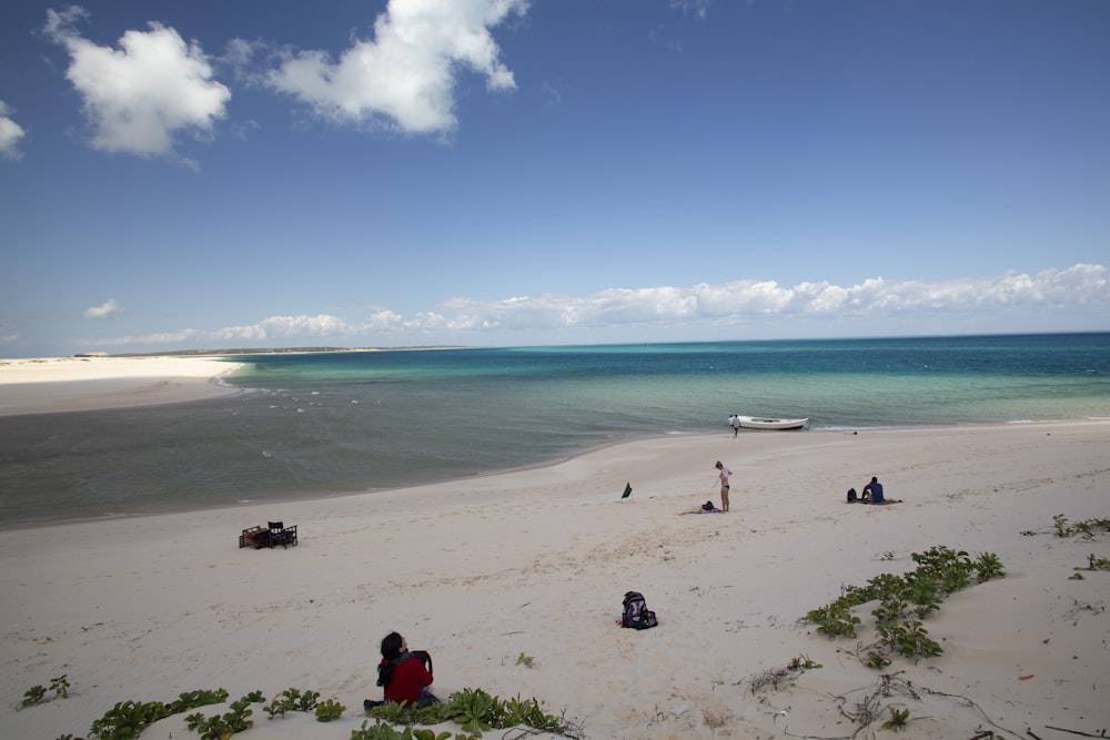 a group of people sitting on top of a sandy beach