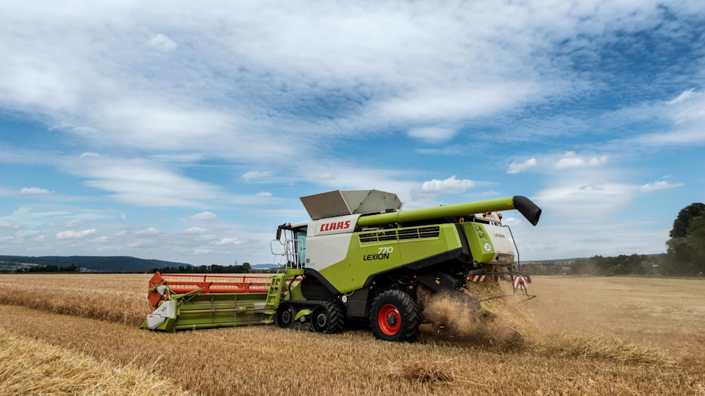 a green and white combine is driving through a field