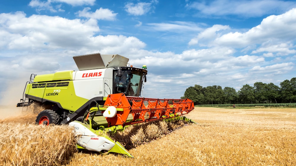 a green and white combine is in the middle of a wheat field