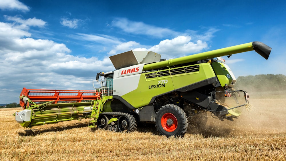 a green and white combine is in the middle of a field