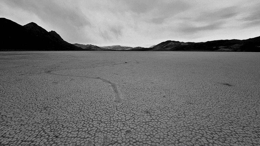 a black and white photo of a desert with mountains in the background