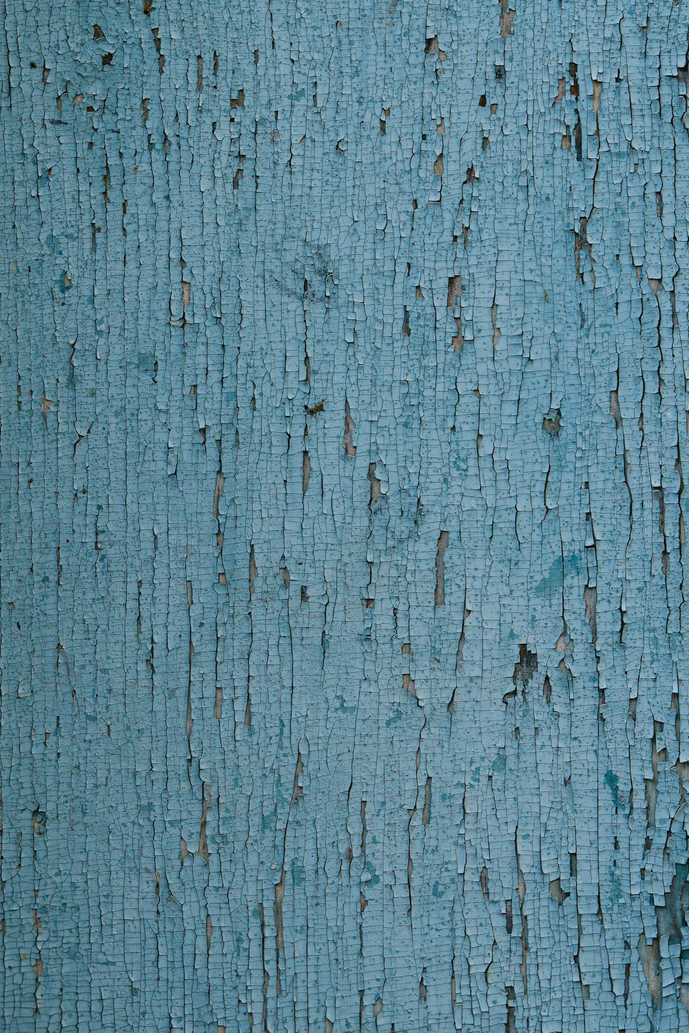 a close up of a blue painted wall with peeling paint