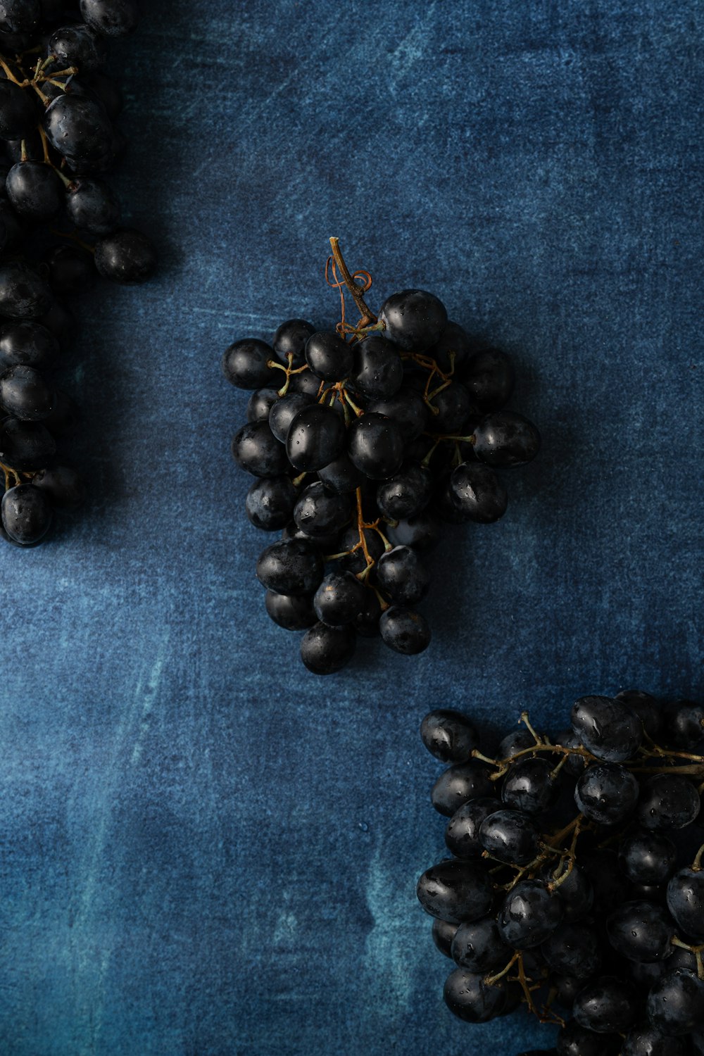 une grappe de raisin posée sur une table bleue