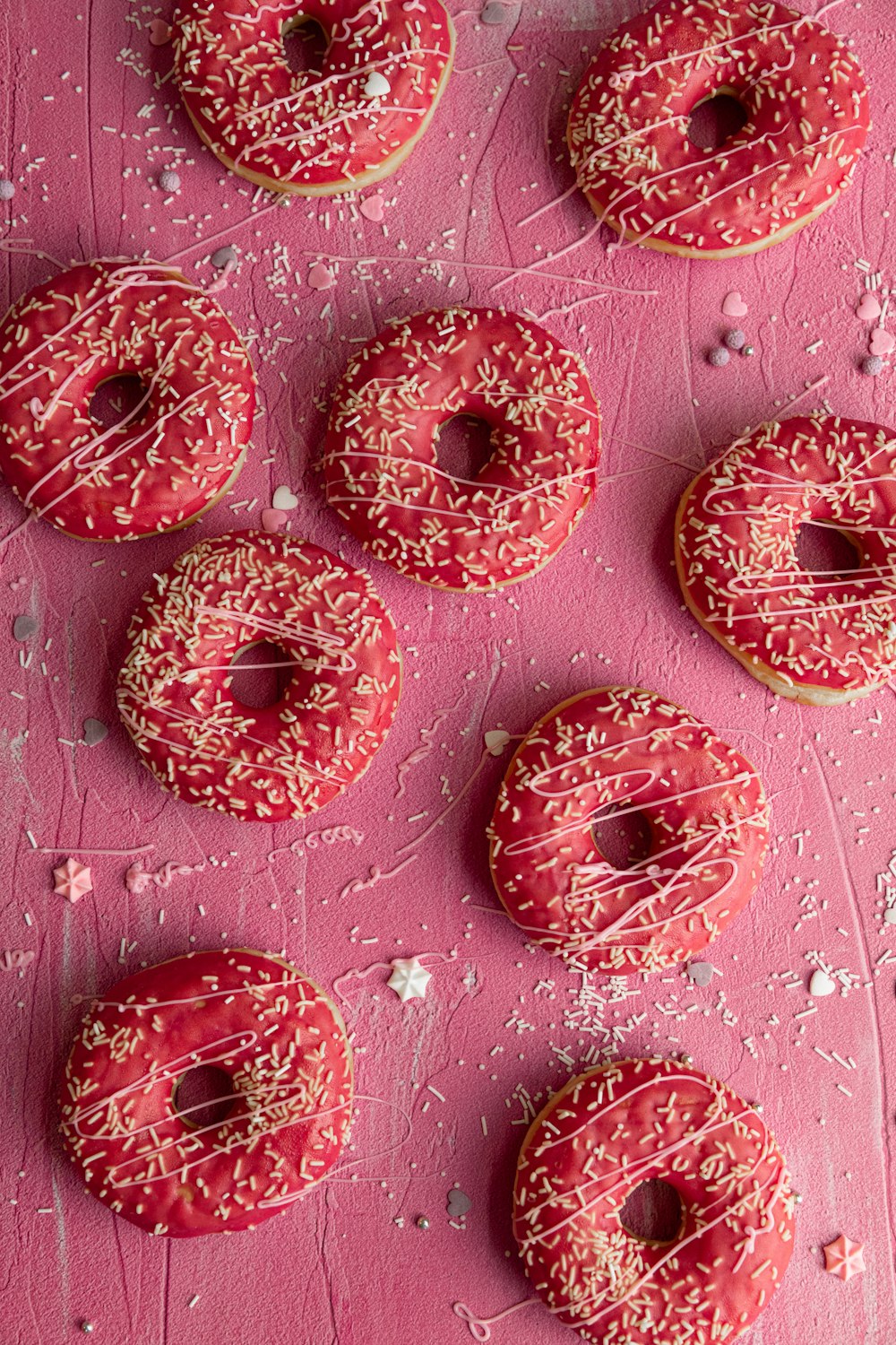 a bunch of doughnuts that are on a pink surface