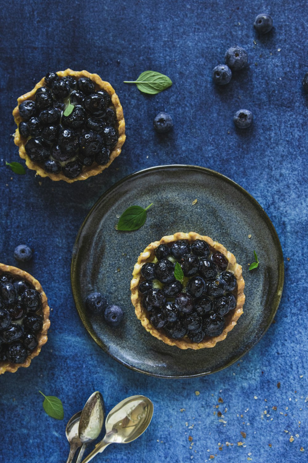 a blueberry tart is on a plate with a spoon