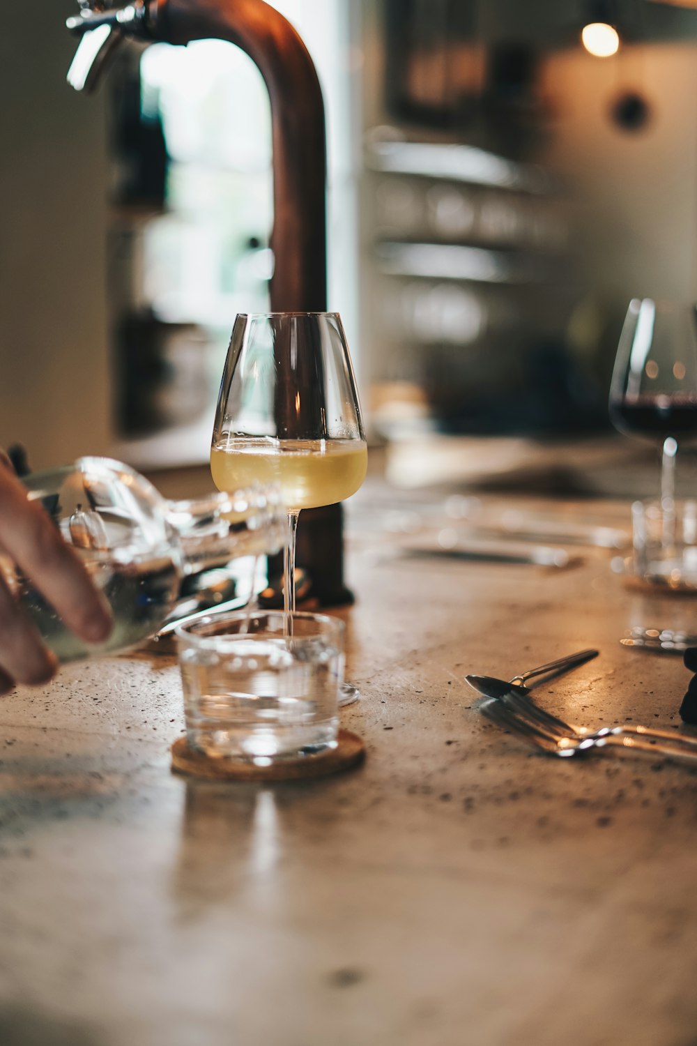 a person pouring a glass of wine from a faucet