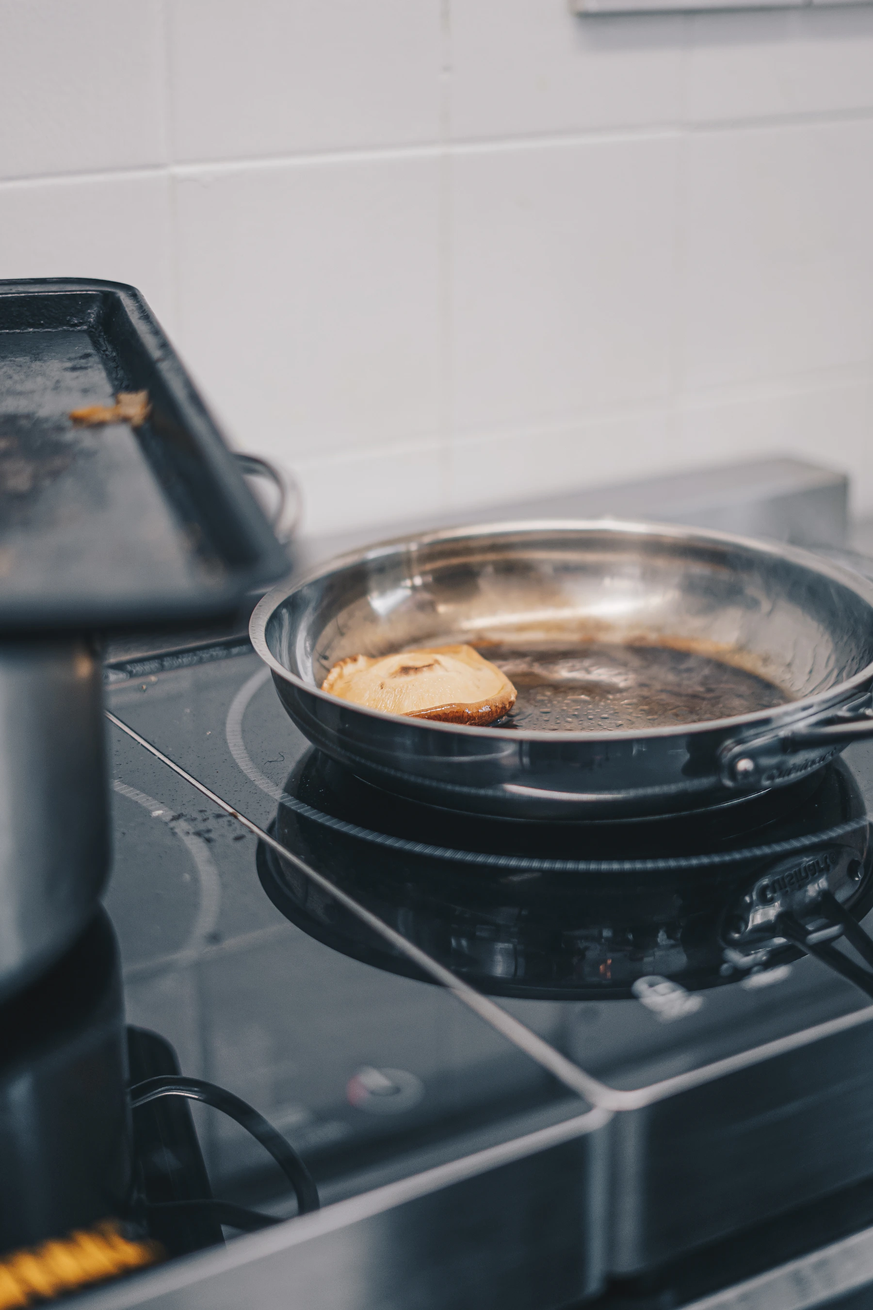 Stainless steel frying pan cooking on a kitchen stovetop