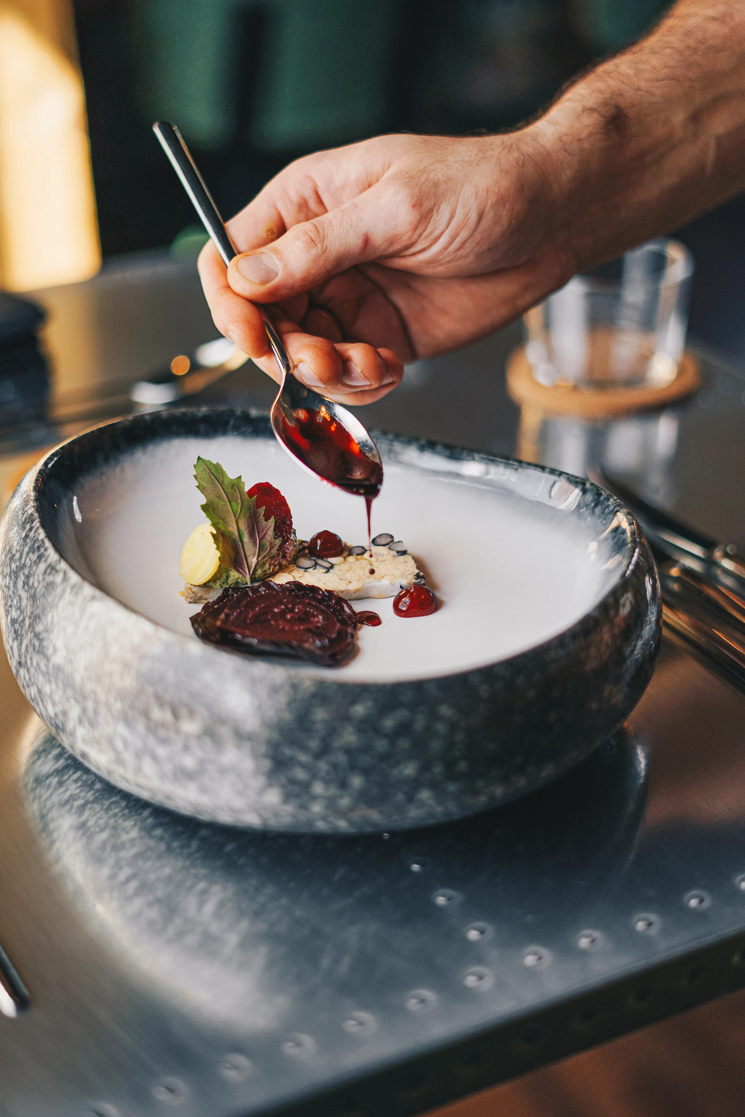 Chef privé dressant une assiette et nappant le plat d’une sauce