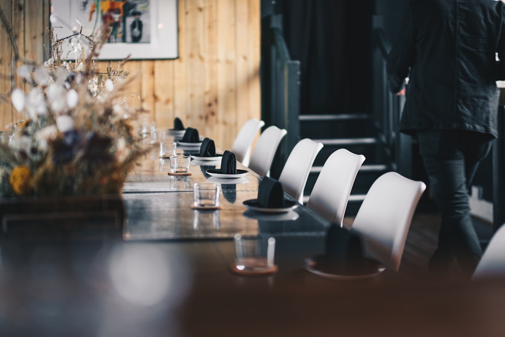 a man walking past a long table with white chairs