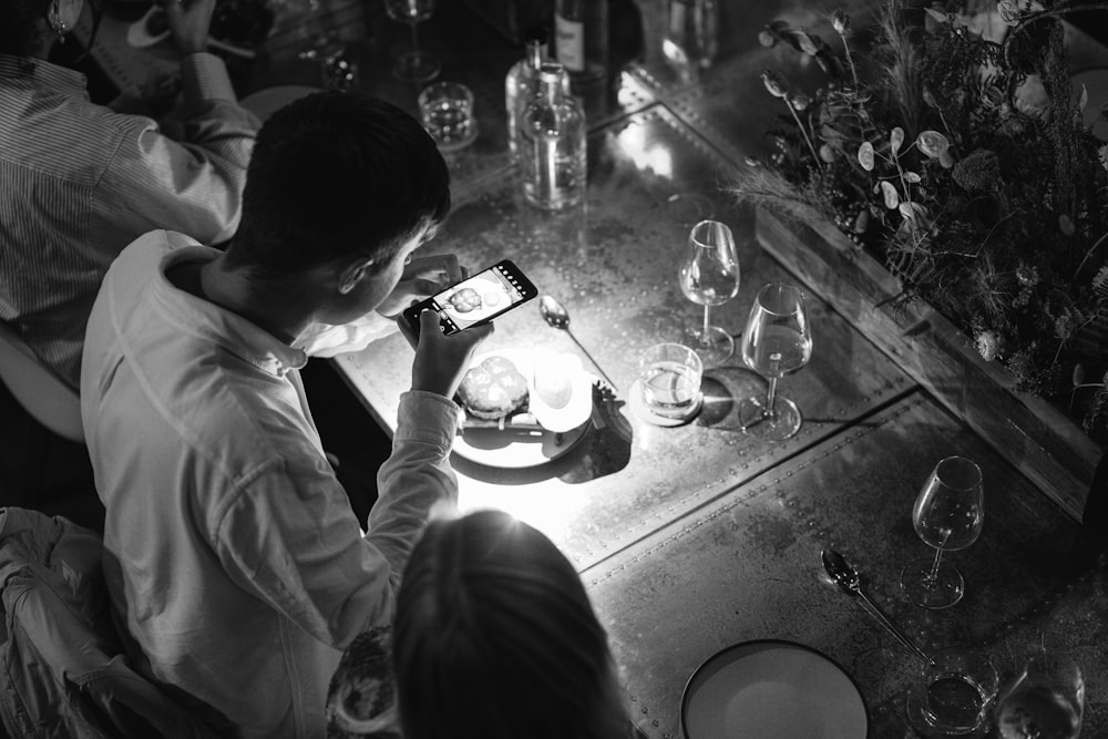 a man and woman sitting at a table looking at a cell phone