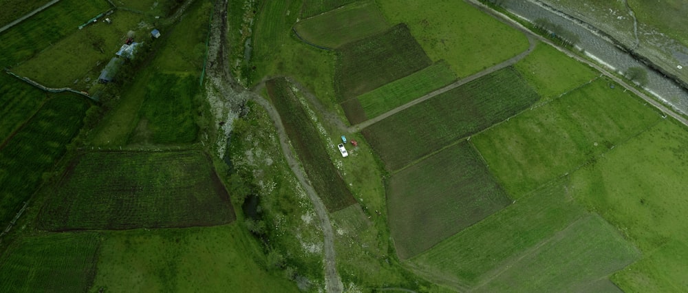 an aerial view of a green field and a road