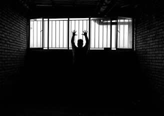 a person standing in a dark room with their hands up