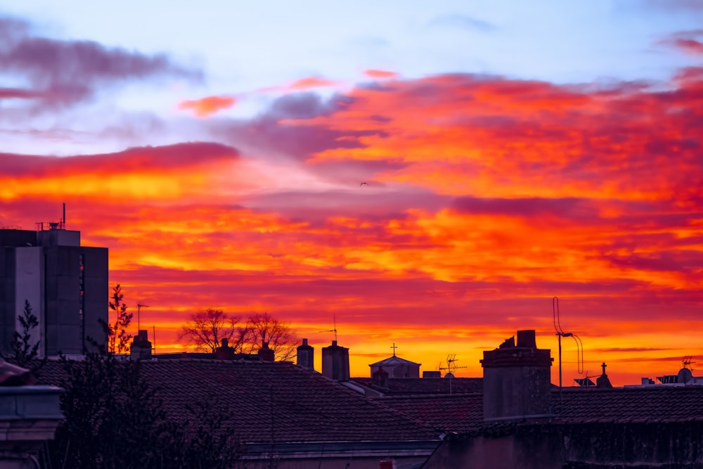 Um pôr do sol vermelho e laranja sobre telhados em uma cidade