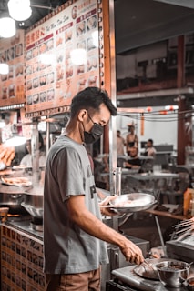 a man wearing a face mask cooking in a restaurant