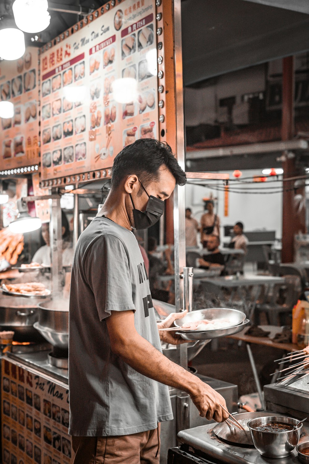 a man wearing a face mask cooking in a restaurant