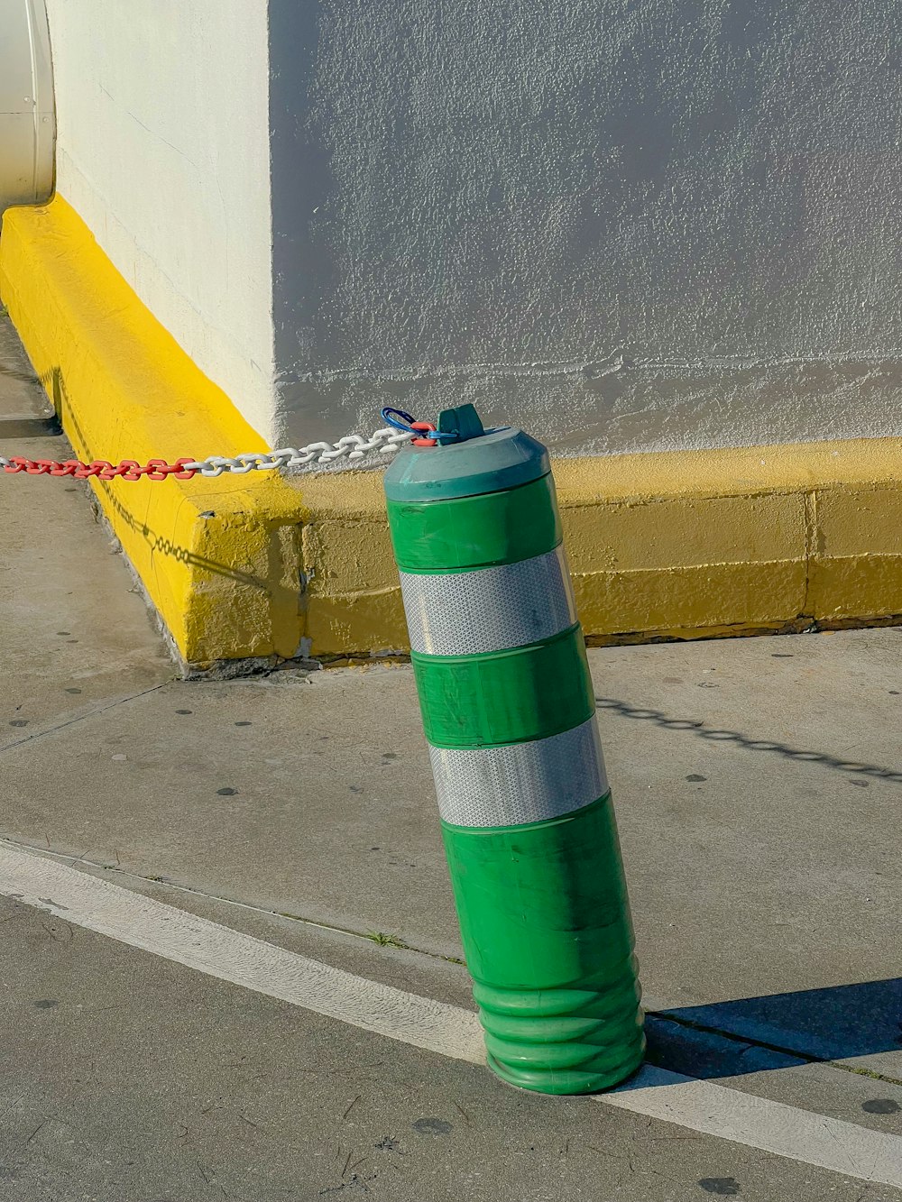 a green and white pole sitting on the side of a road