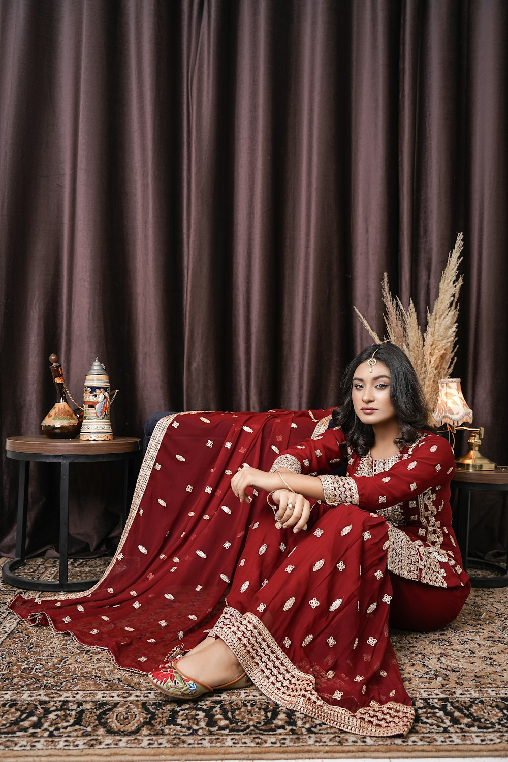 a woman in a red dress sitting on a rug