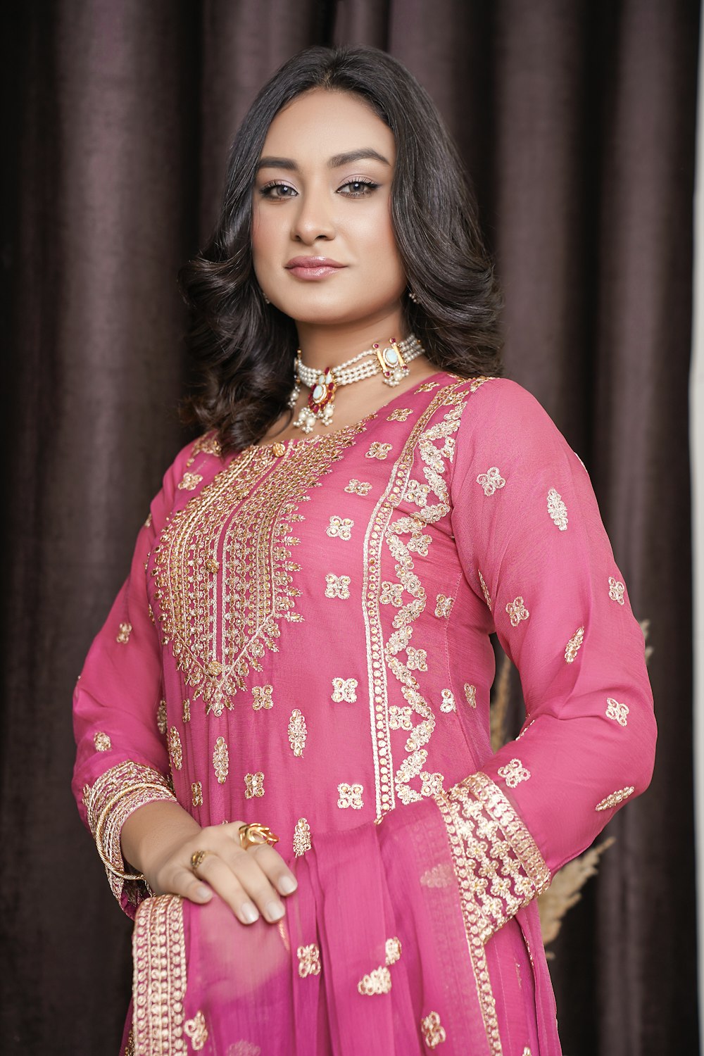 a woman in a pink outfit standing in front of a curtain