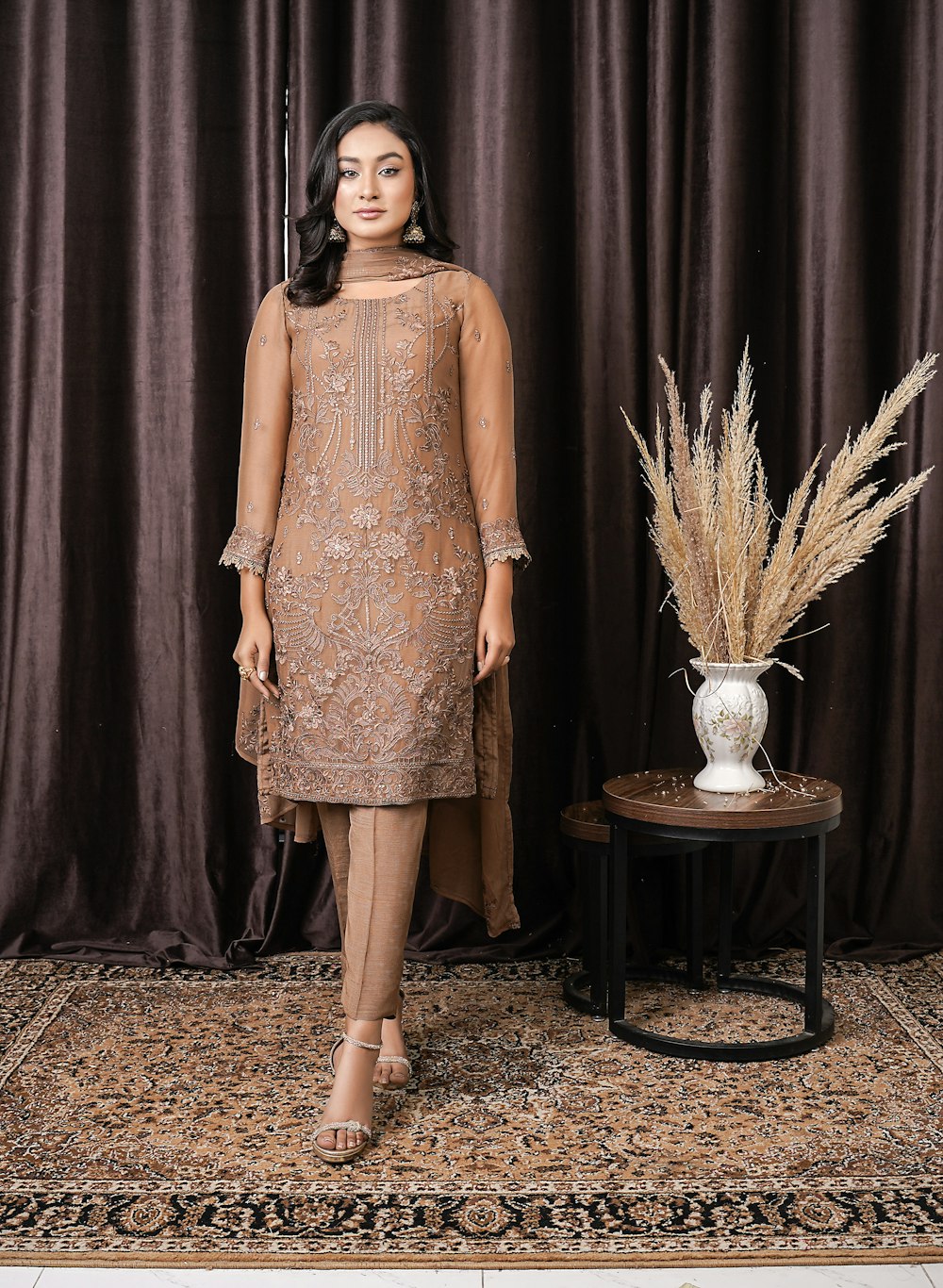 a woman standing in front of a brown curtain