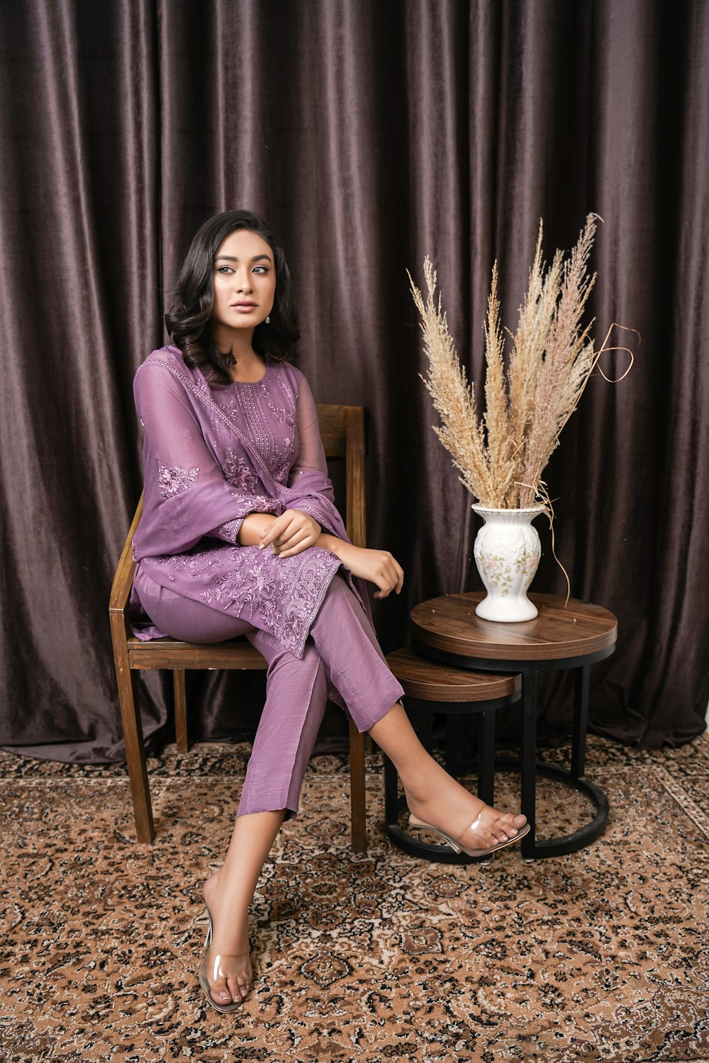 a woman sitting in a chair next to a vase