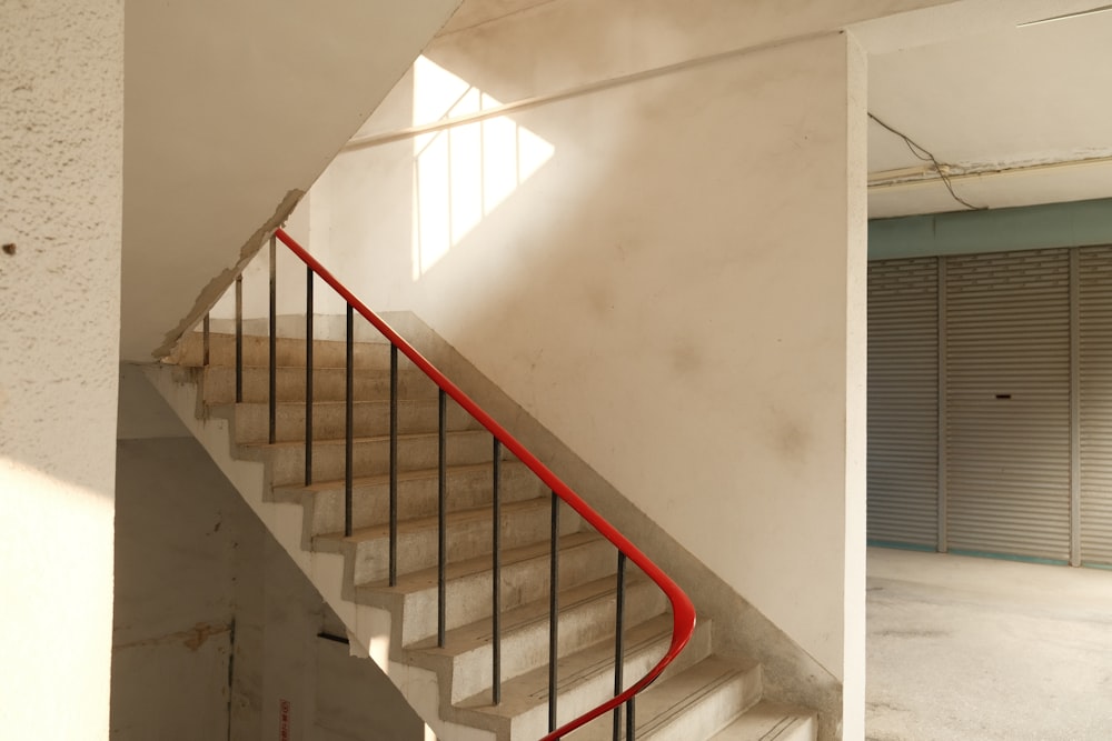 a white staircase with a red hand rail