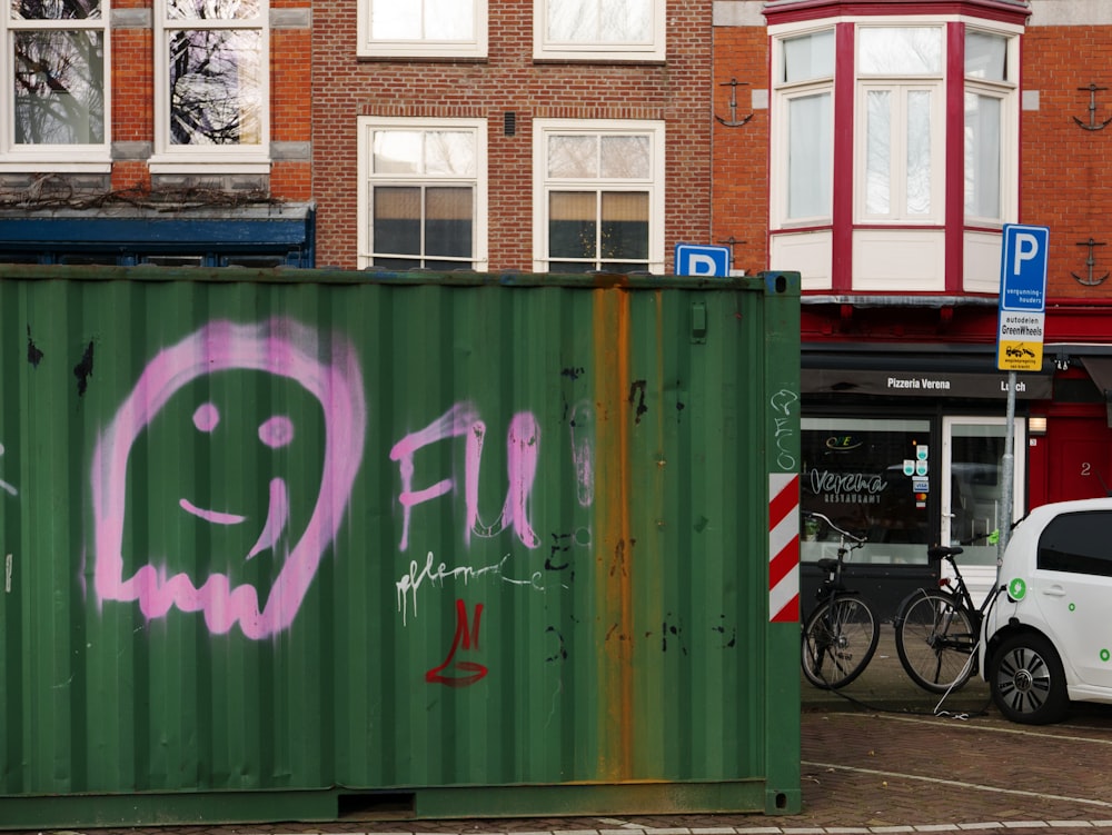 a green shipping container with graffiti on it