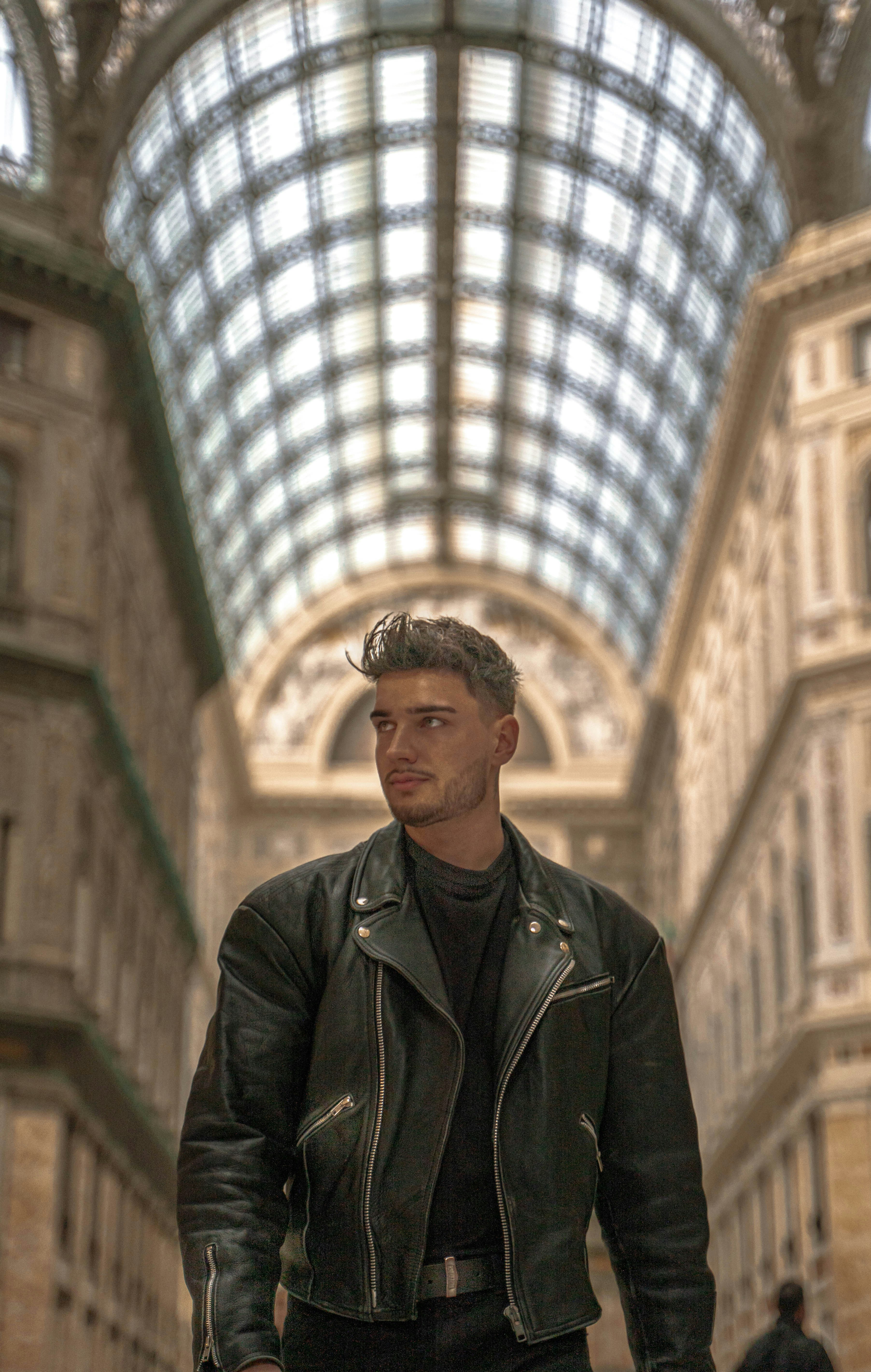 a man in a leather jacket is walking down the street