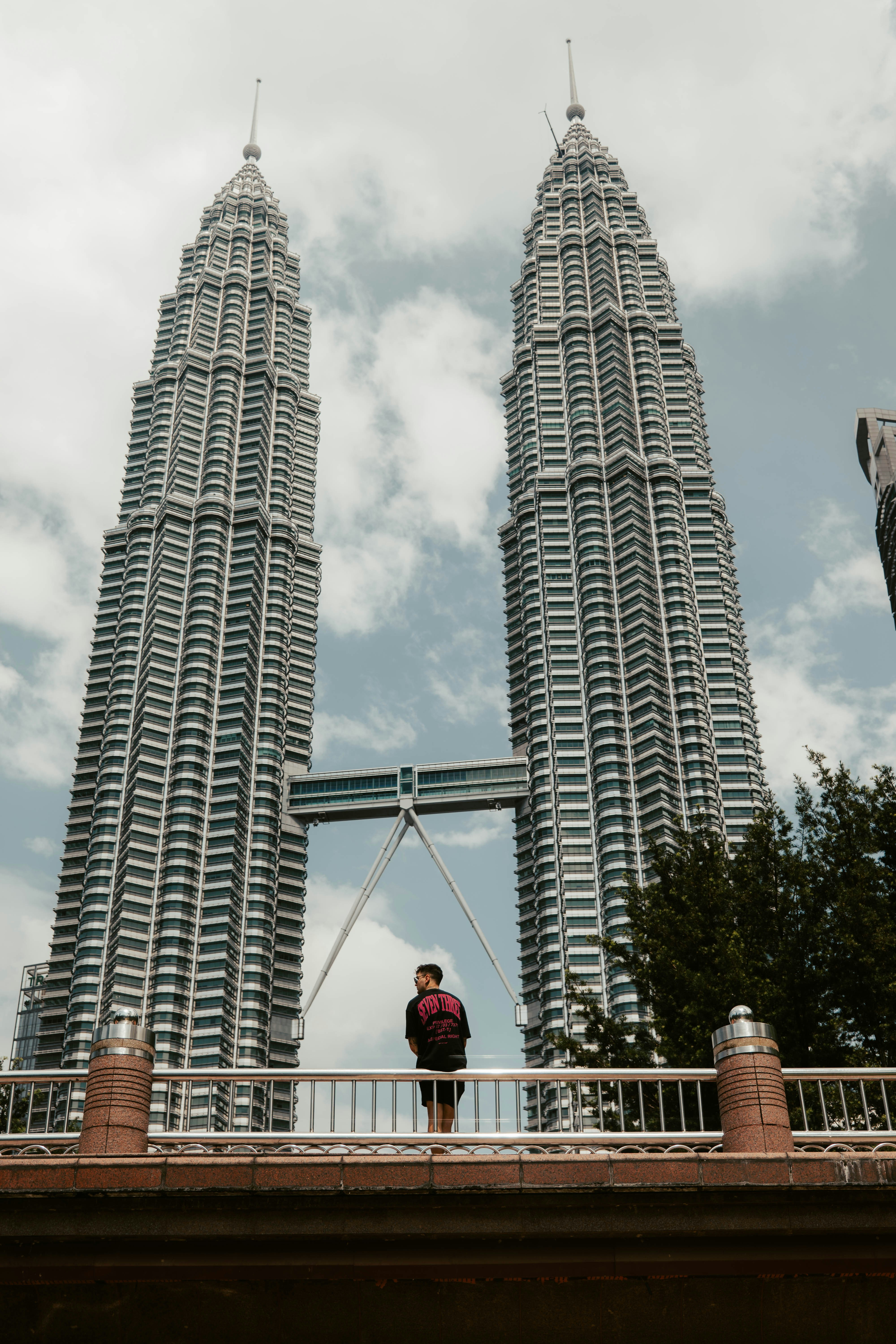a man standing on a bridge in front of two tall buildings