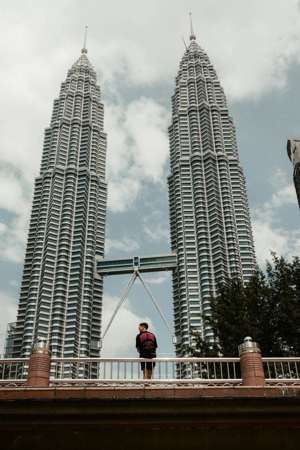 a man standing on a bridge in front of two tall buildings