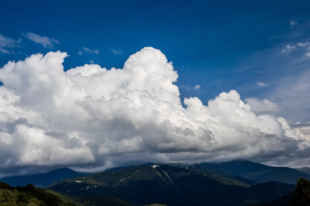 a large cloud is in the sky over a mountain