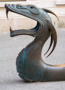 a bronze statue of a dragon on a sidewalk