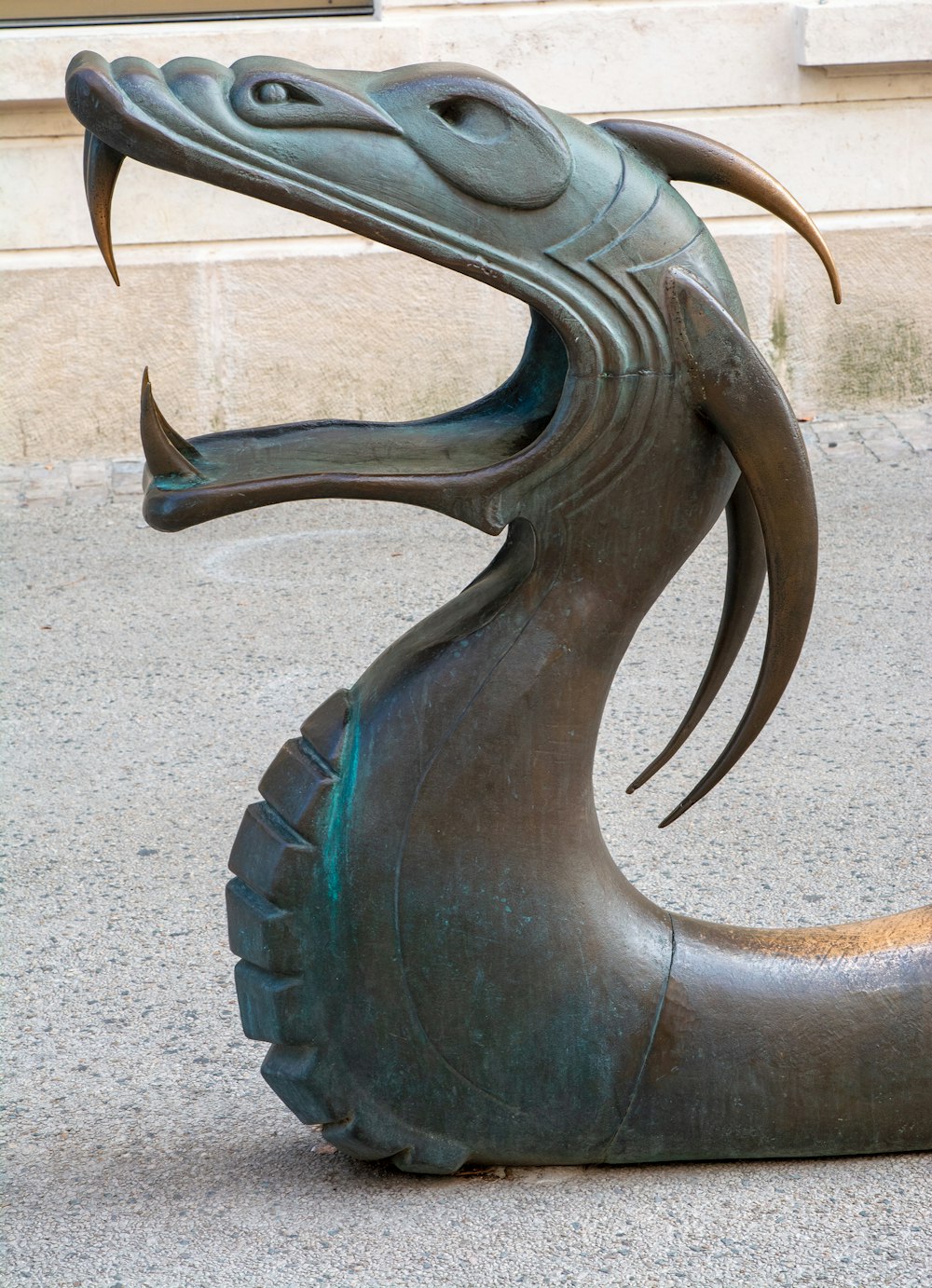 a bronze statue of a dragon on a sidewalk