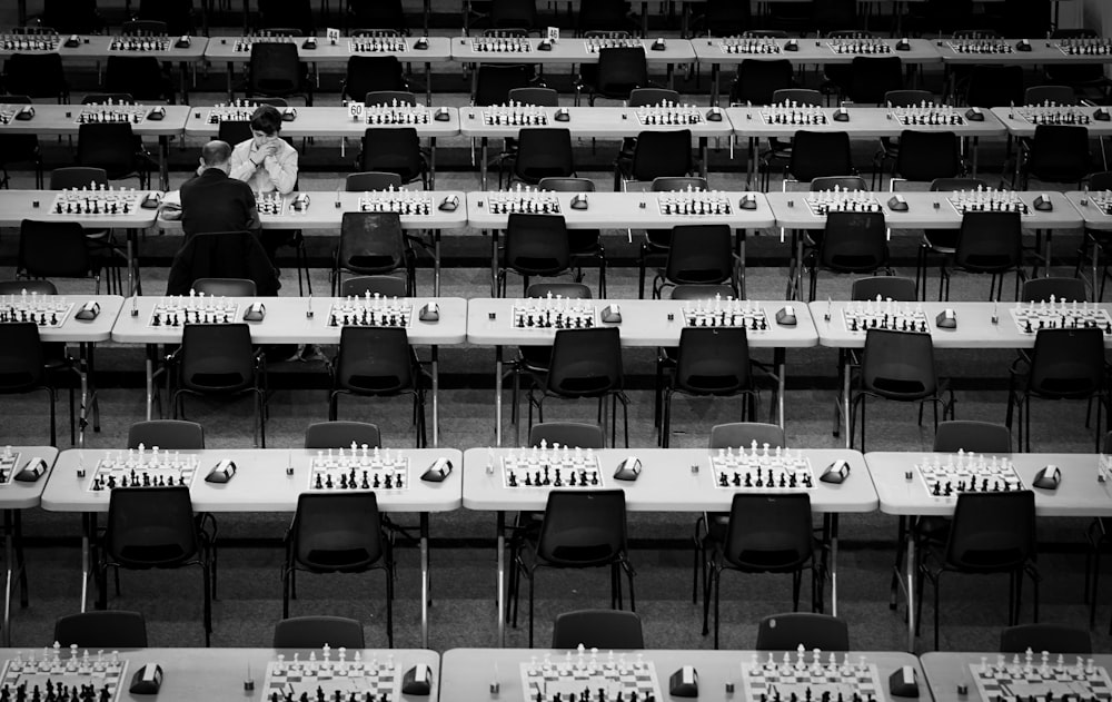 a black and white photo of a man standing in front of rows of tables