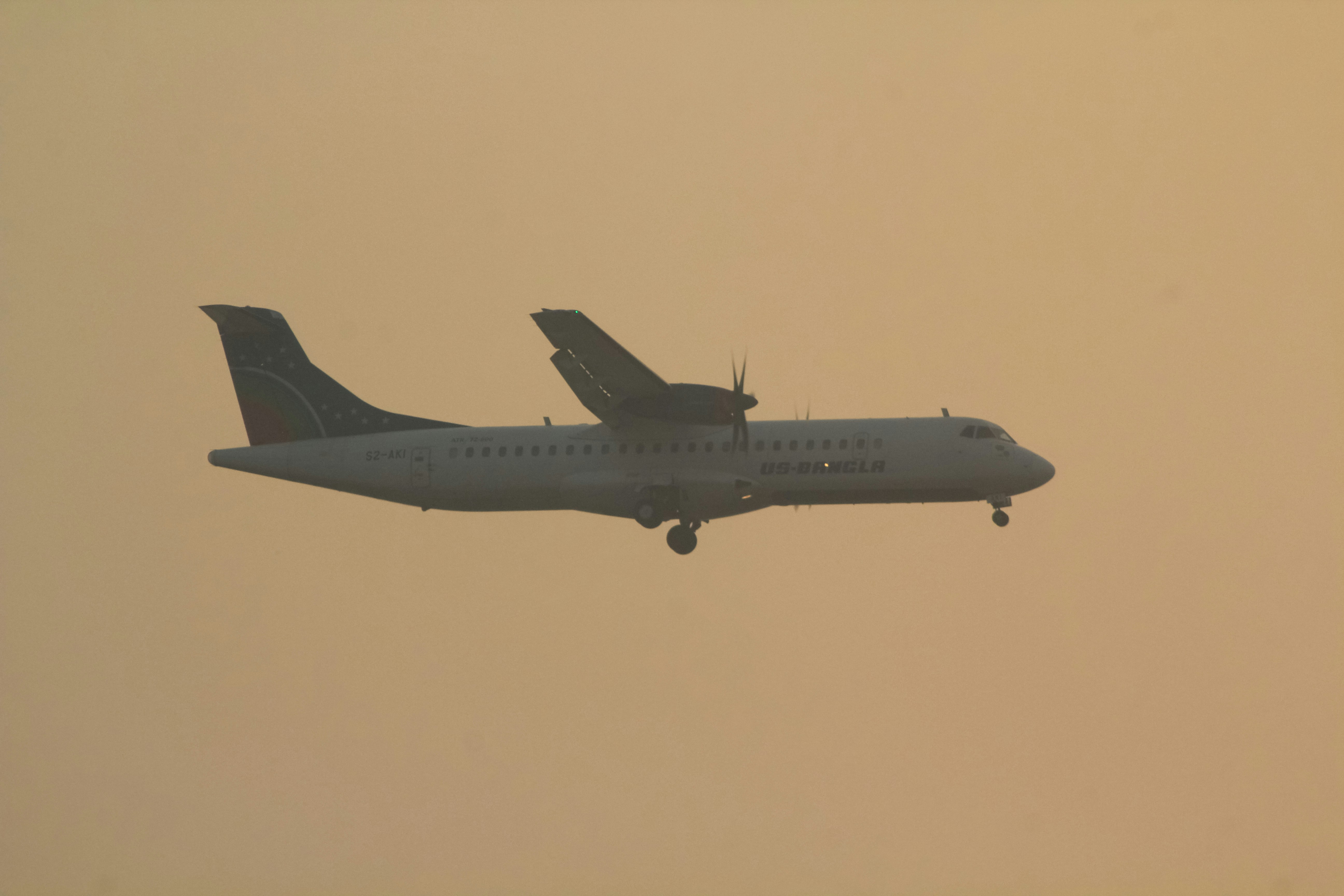 a large passenger jet flying through a hazy sky, US-Bangla