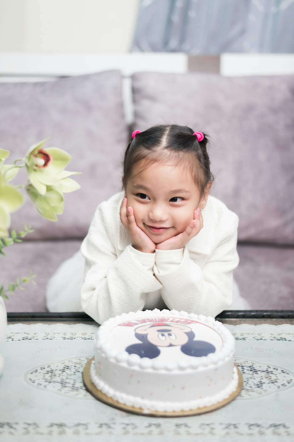 a little girl sitting in front of a cake