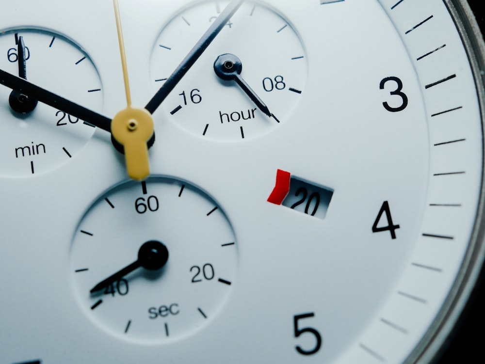 a close up of a white clock with yellow hands