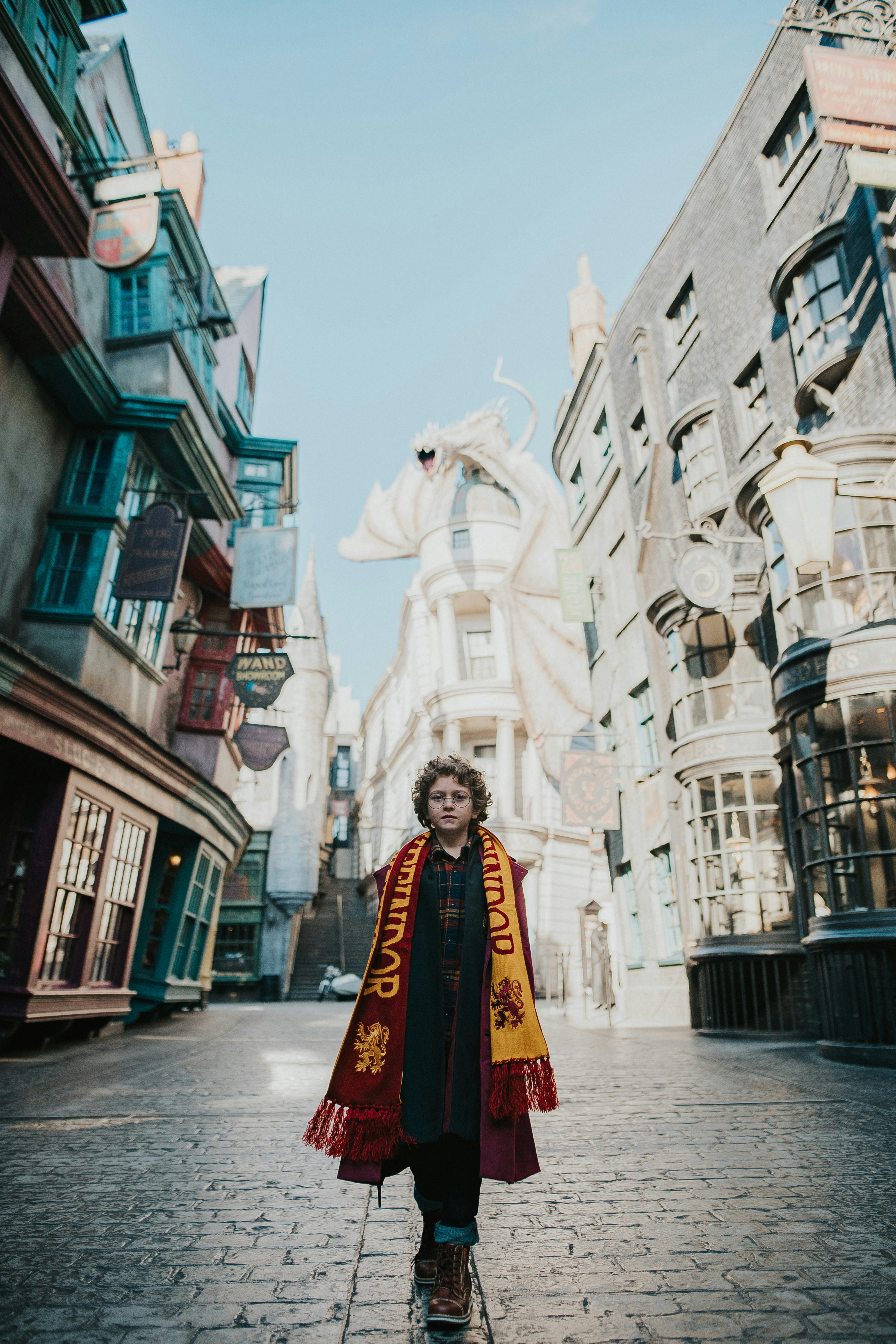 a child in a harry potter robe standing on a brick street