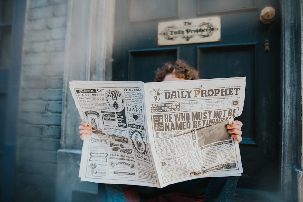 a woman reading a newspaper in front of a door