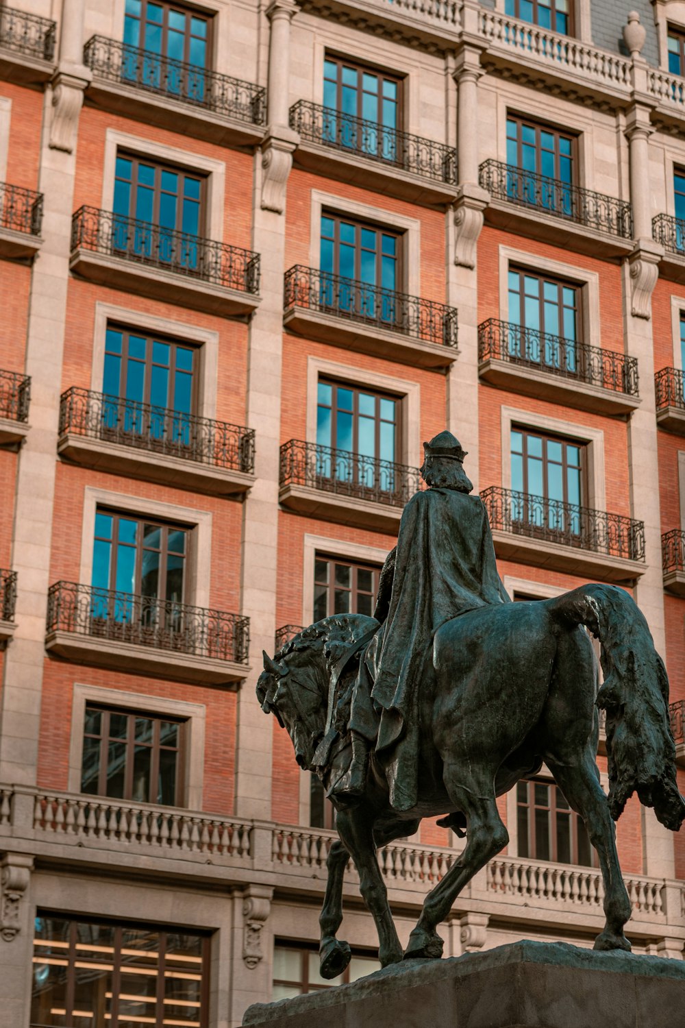 a statue of a man riding a horse in front of a building