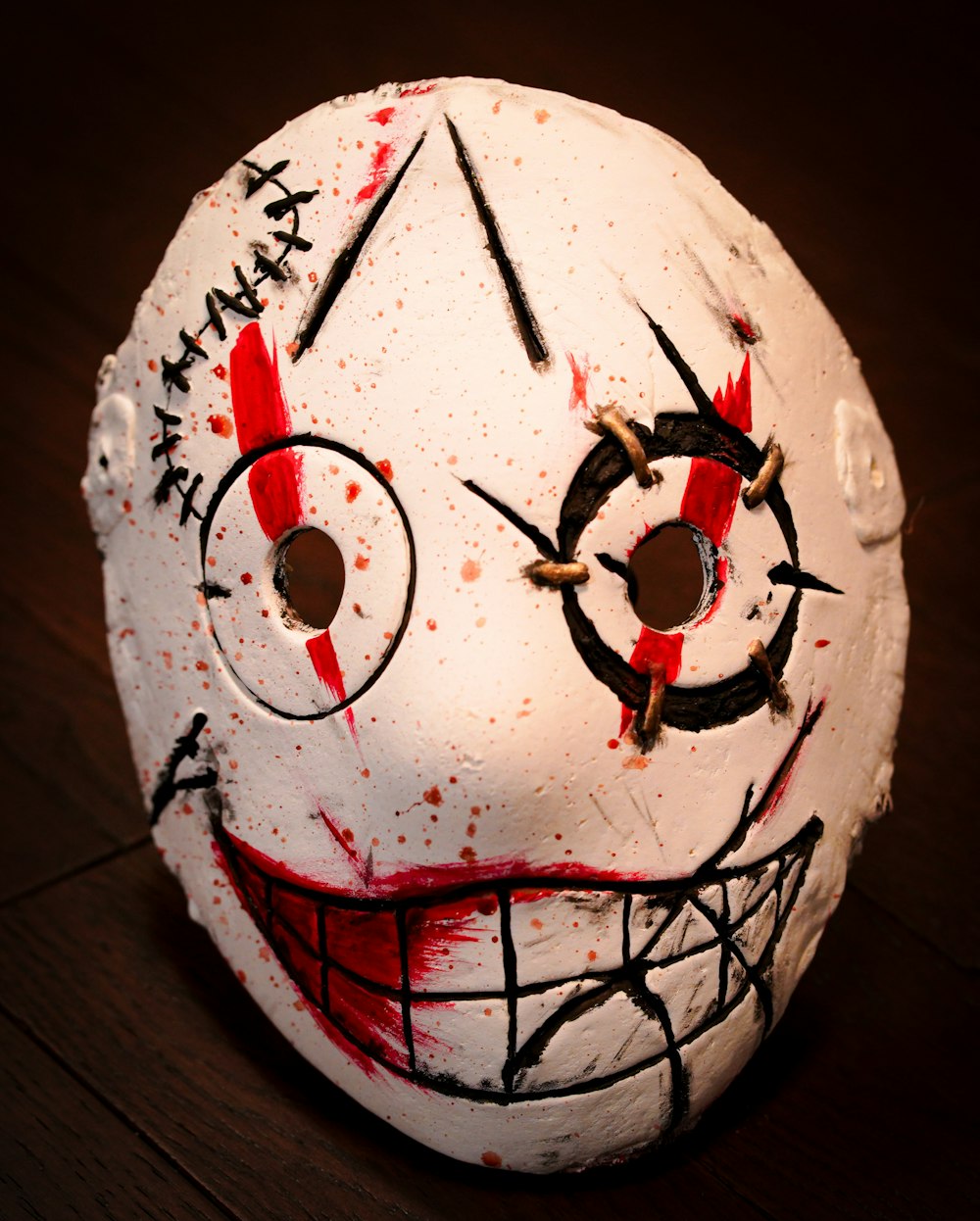 a white mask with red and black paint on it