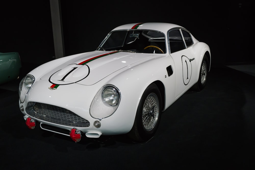 a white sports car on display in a dark room