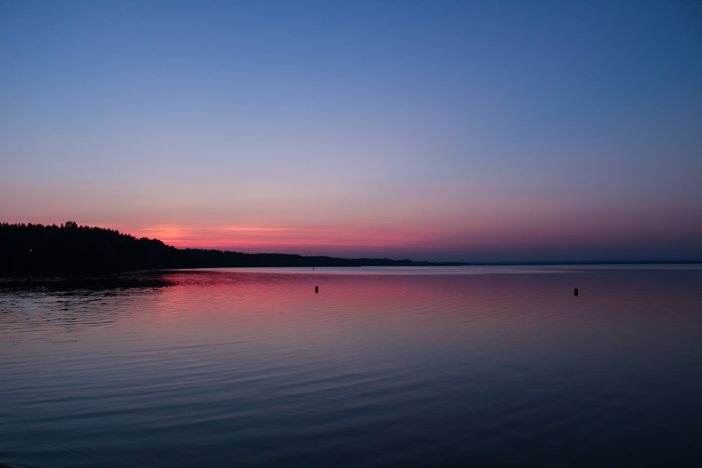 un plan d’eau avec un coucher de soleil en arrière-plan