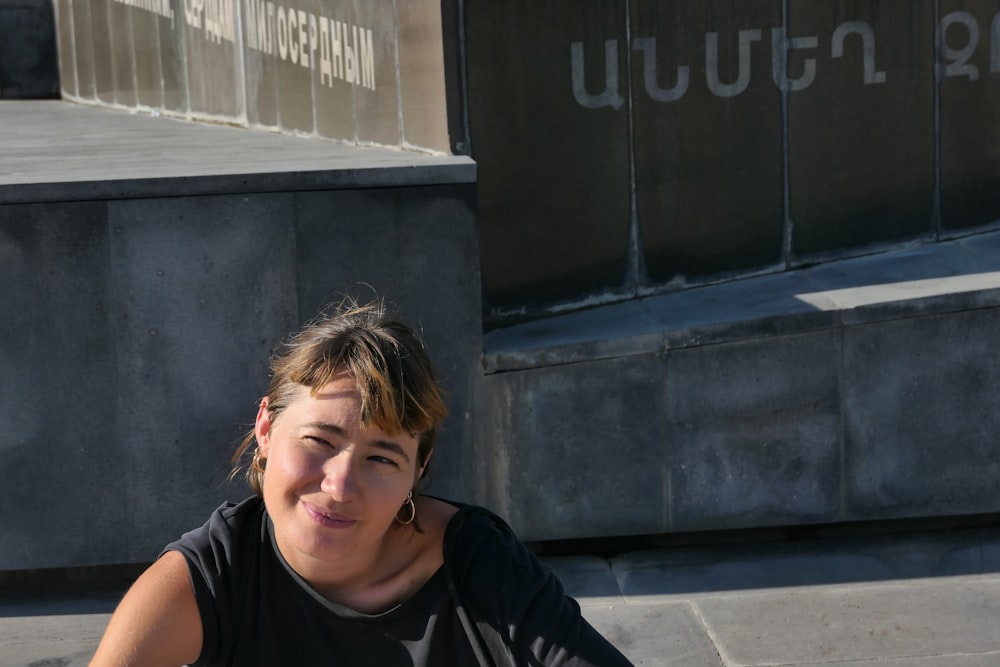 a woman sitting on the ground in front of a building