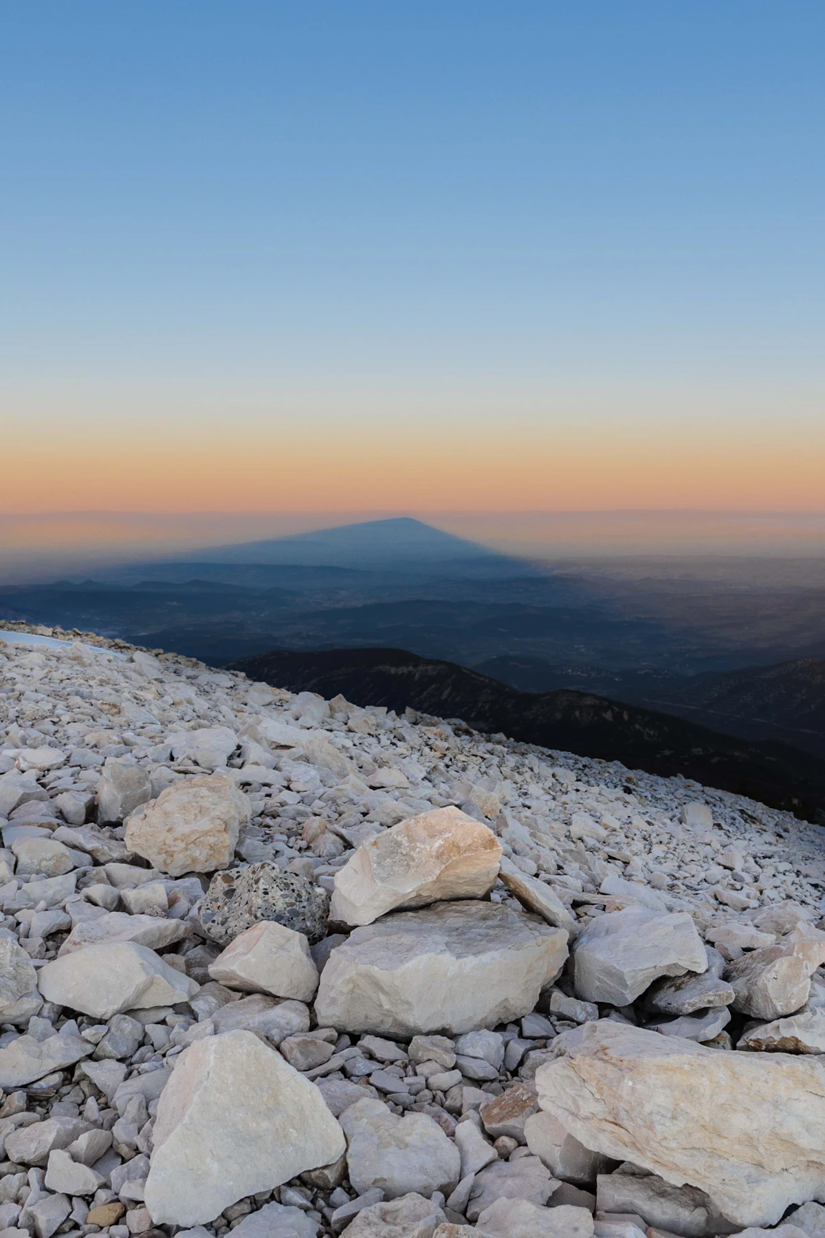 White limestone scree near the top of Mont Ventoux, with the mountain's shadow on the haze beyond