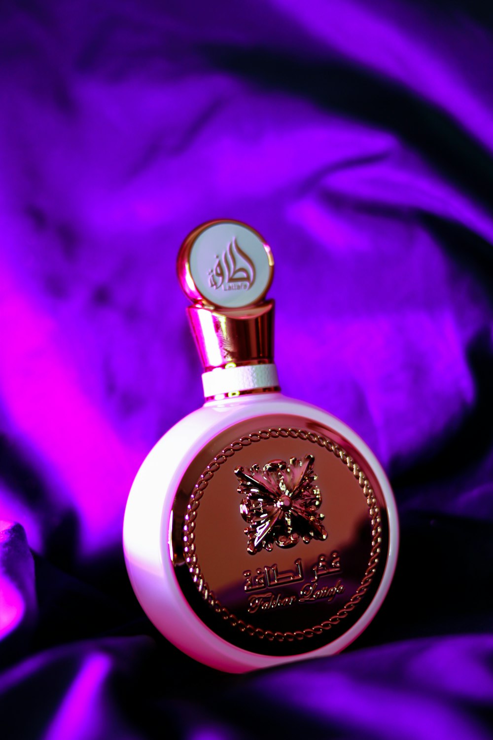 a bottle of perfume sitting on a purple cloth