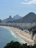 a crowded beach with mountains in the background
